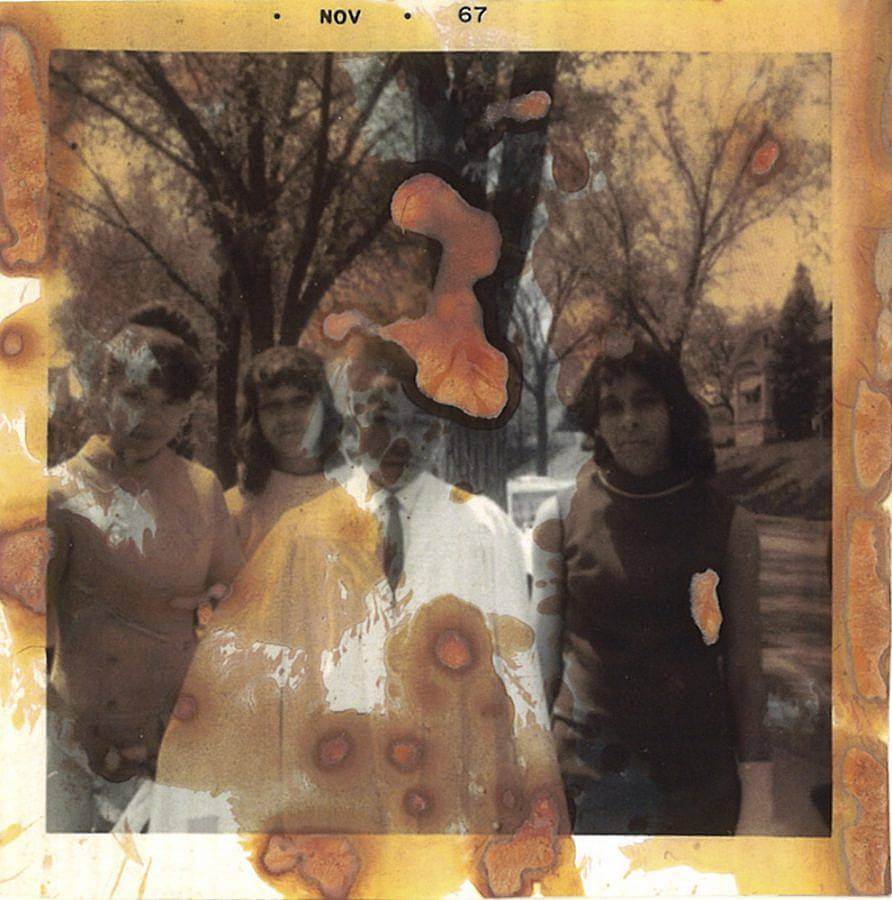 Image Description: This is a photograph from November is 1967 of a young boy's confirmation. He is in the center of the photograph in white robes with three well-dressed women standing behind him. The photograph itself is deteriorating.