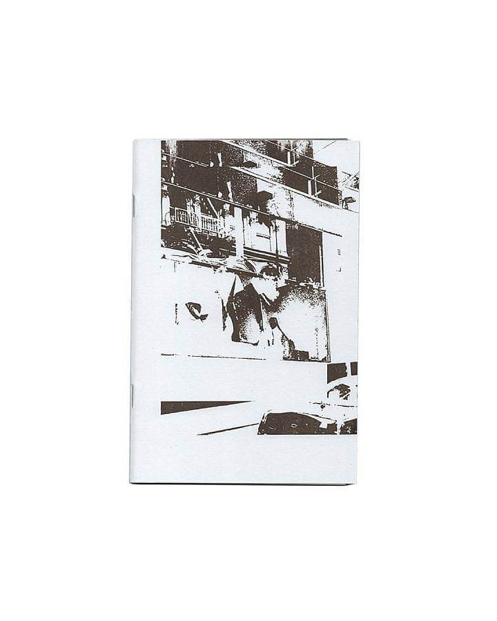 image description: This is a photograph of a book published by Soup Press in 2019. The cover of the book is pictured it has a very high contrast photograph screen printed in brown ink onto white paper. The image features an obscured window and shelving units.